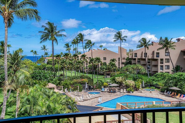Un resort con múltiples piscinas, palmeras y una vista despejada del océano.
