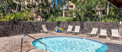 A swimming pool with lounge chairs and a stone wall.