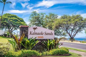 A sign for Kamaole Sands with a beach view.