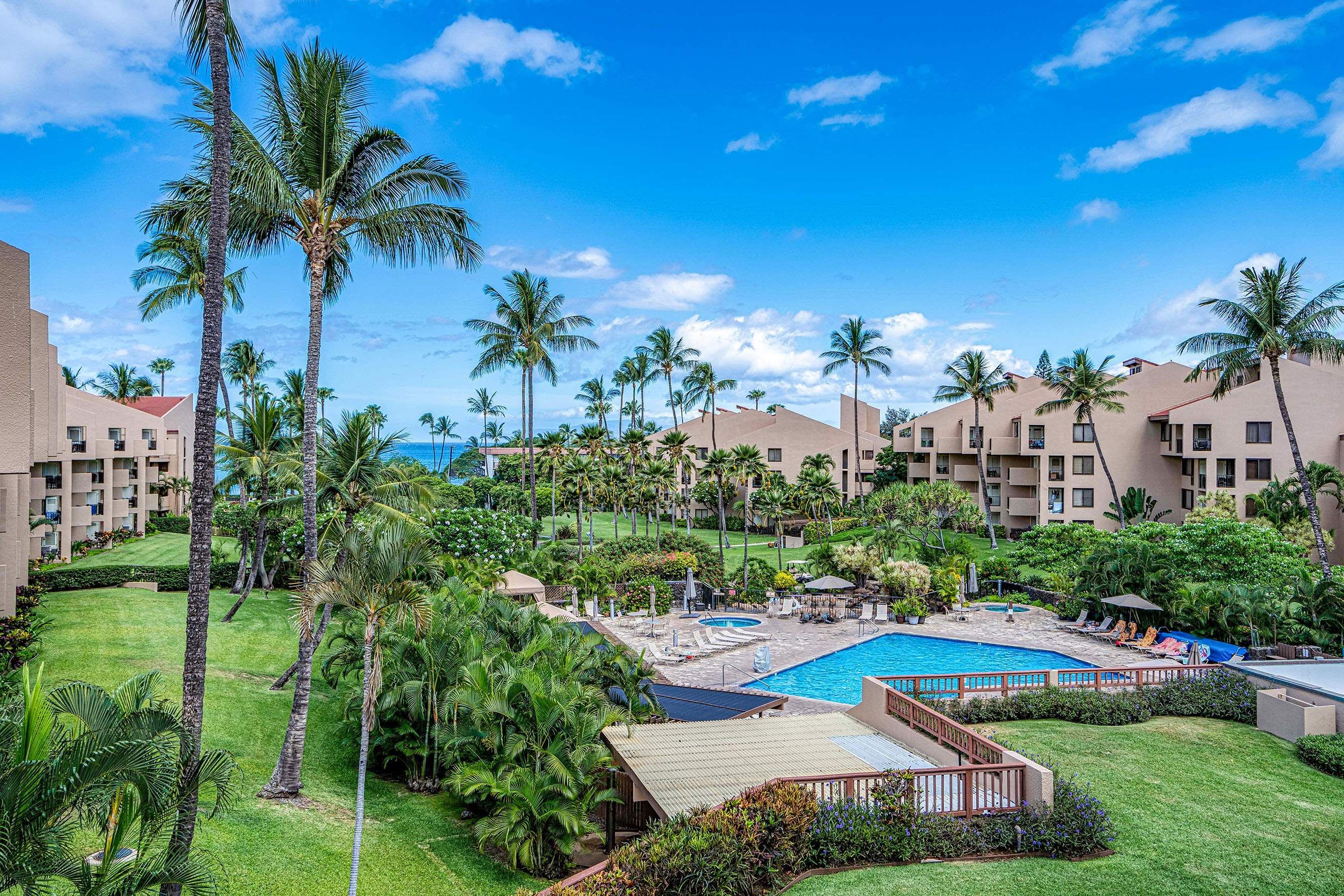 A resort with multiple buildings, a swimming pool, and palm trees.