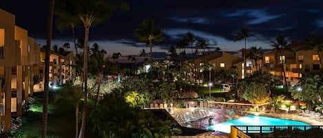 A resort with multiple buildings, a swimming pool, and palm trees.