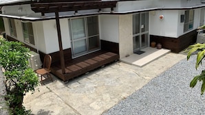 Une maison moderne avec un toit recouvert de tuiles blanches, de grandes fenêtres en verre et une terrasse en bois.