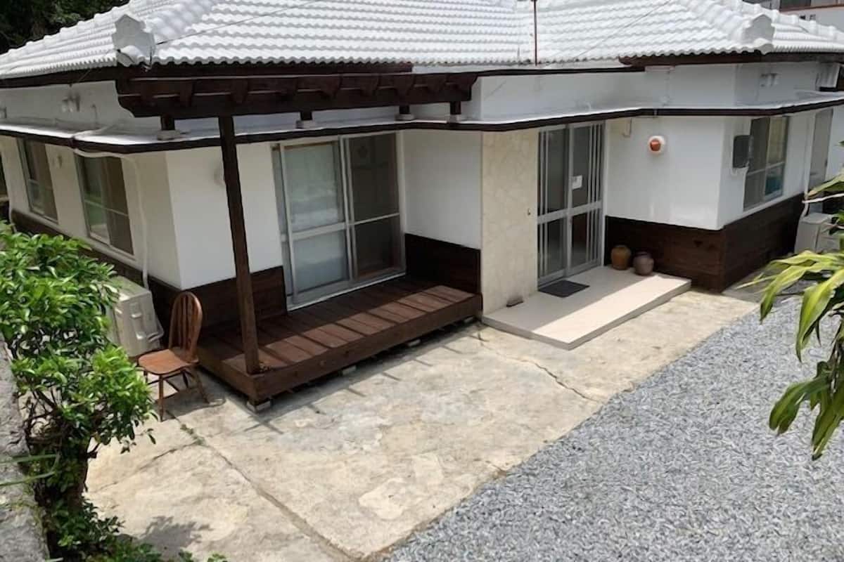 A house with a tiled roof, a wooden porch, and a small garden area.