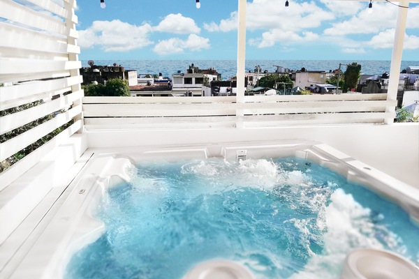 Exciting hot tub on rooftop terrace, with ocean view, next to outdoors shower.