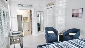 A bedroom with a bed, two chairs, a small table, and a mirror. - BY THE BEACH WITH A POOL! PRIVATE GUEST STUDIO APT. WITH A FULL KITCHEN & BATH! (Naples)