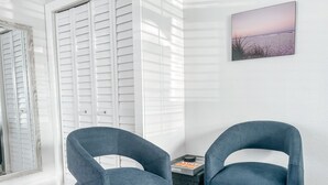 A room with two dark blue armchairs, a small side table with a book, and a framed picture of a beach scene on the wall. - BY THE BEACH WITH A POOL! PRIVATE GUEST STUDIO APT. WITH A FULL KITCHEN & BATH! (Naples)