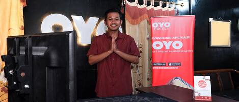 A man standing in front of a display with a large 'OYO' sign and a red banner advertising a mobile app.