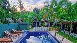 A rectangular swimming pool with a tiled deck, surrounded by palm trees and a small pavilion. - Max Safari Villa (Udawalawa)