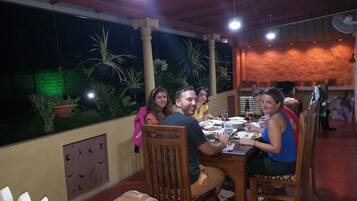 A group of people dining at an outdoor restaurant with a view of the garden and a brick wall.
