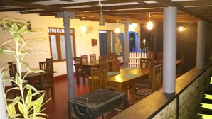 A dining area with wooden tables and chairs, a potted plant, and a staircase leading to another level. - Max Safari Villa (Udawalawa)