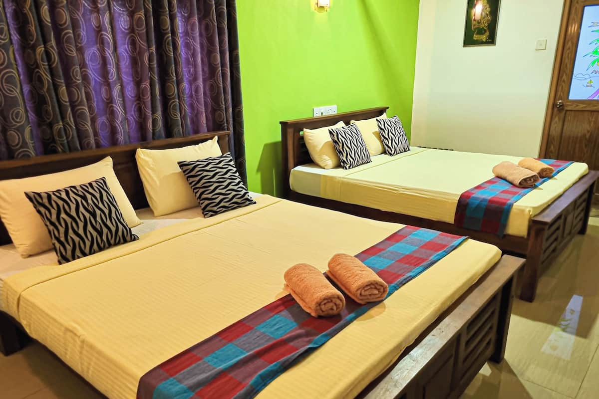 A hotel room with two beds, each with a different patterned pillow and a rolled towel on the bed.