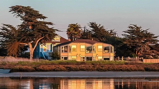 A two-story house with a balcony, surrounded by trees and a body of water. - 2nd floor, panoramic views, 2-person soaking tub, fireplace (Moss Landing)