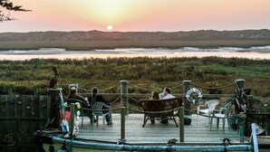A deck with chairs overlooking a body of water at sunset. - 2nd floor, panoramic views, 2-person soaking tub, fireplace (Moss Landing)