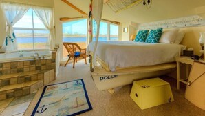 A bedroom with a bed, a window with a view, a bathtub, and a small table. - 2nd floor, panoramic views, 2-person soaking tub, fireplace (Moss Landing)