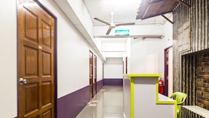 A hallway with wooden doors, a reception desk, and a ceiling fan. - Hotel O Purple Town (Sekinchan)