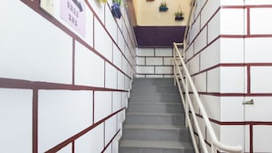 A staircase with a handrail, white walls with brown accents, and a sign with dates. - Hotel O Purple Town (Sekinchan)