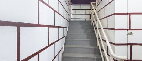A staircase with a handrail, white walls with brown accents, and a sign with dates.
