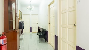 A hallway with a fire extinguisher, a bench, and doors leading to rooms. - Hotel O Purple Town (Sekinchan)