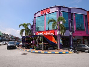 A hotel with a purple facade, a large sign reading "Hotel Purple Town," and a flower display in front. - Hotel O Purple Town (Sekinchan)
