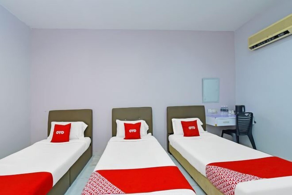 Habitación de hotel con tres camas individuales, un escritorio y una silla.