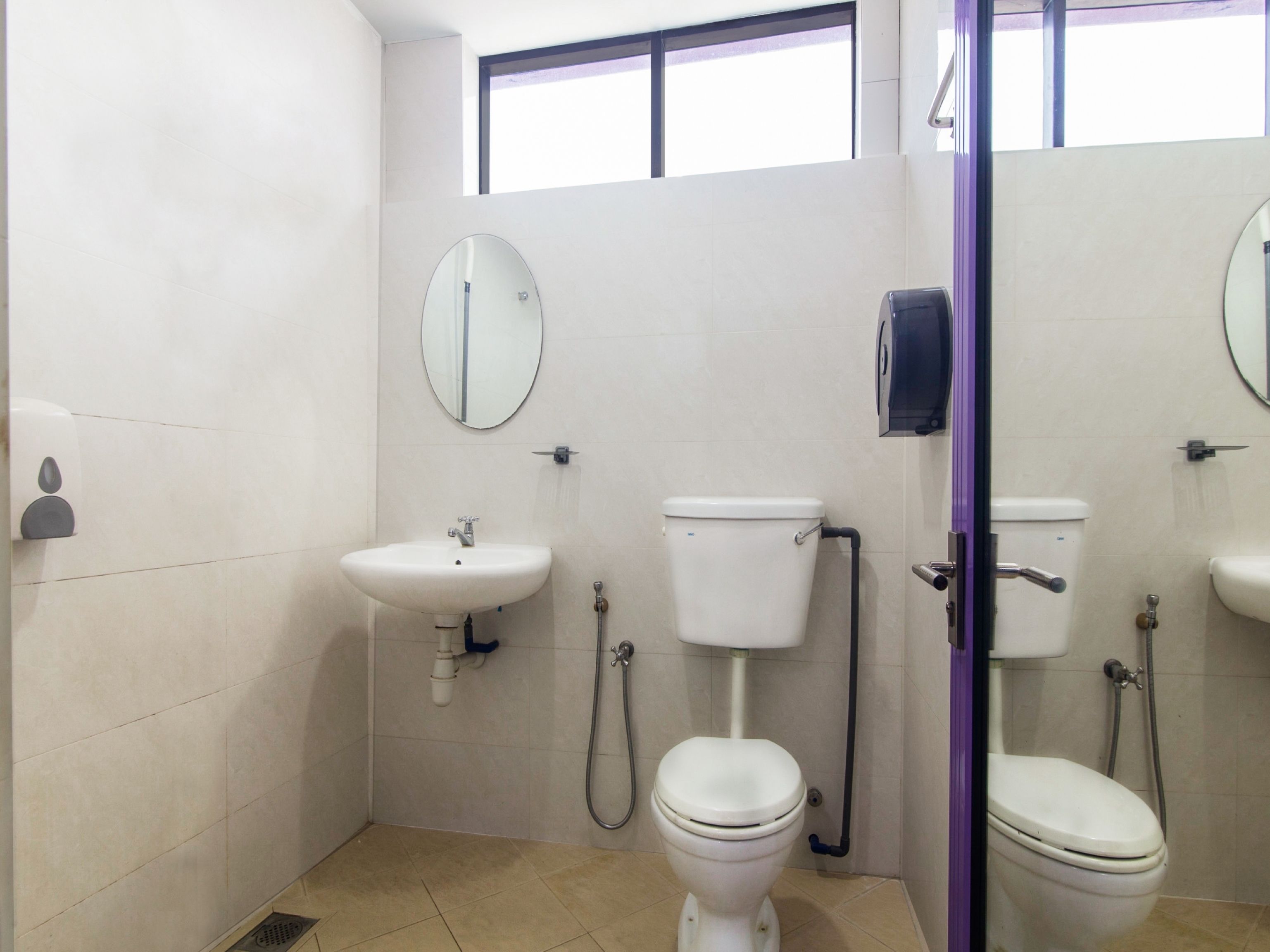 A bathroom with two toilets, a sink, and a mirror.