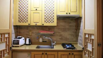 Una cocina compacta con gabinetes de madera, un microondas integrado, una estufa a gas y un lavabo.
