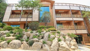 A multi-story building with balconies, large windows, and a rocky landscape in front. - Hotel de forRe (Daegu)