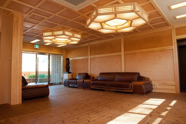 Un hall d’entrée spacieux, doté d’un plancher en bois, d’un canapé en cuir et de luminaires hexagonaux au plafond.