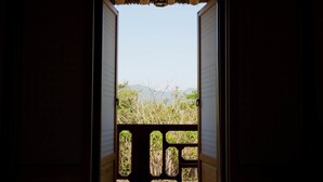 An open doorway with a view of a natural landscape, including trees and distant mountains. - Hotel de forRe (Daegu)