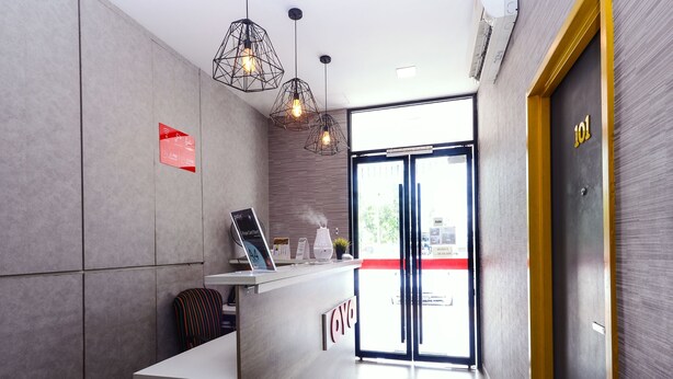 A reception area with a modern design, including a reception desk, geometric pendant lights, and a large glass door leading outside. - OYO 876 Hotel Sanctuary (Petaling Jaya)