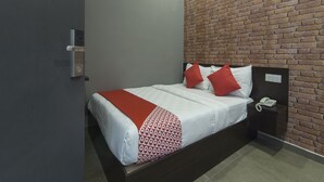 A hotel room with a brick-patterned wall, a bed with white bedding and red pillows, a bedside telephone, and a dark-colored nightstand. - OYO 876 Hotel Sanctuary (Petaling Jaya)