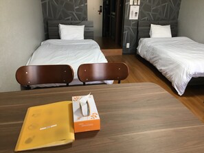 Habitación de hotel con dos camas, una mesa de madera y una silla. Hay una caja sobre la mesa.