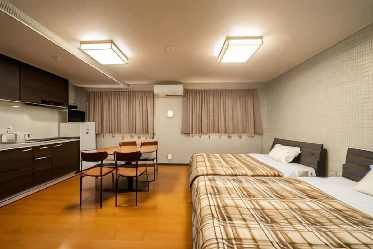 Une chambre dâhĂŽtel compacte comprenant un coin cuisine, un espace repas, un lit et une salle de bain.