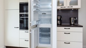A modern kitchen with white cabinetry, a built-in oven, and a coffee maker. - Vacation apartment top right - Haus Fallen Anker in Neuharlingersiel (Neuharlingersiel)