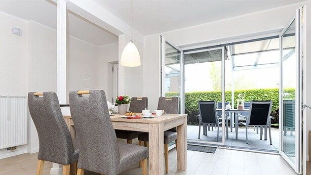 A modern dining area with a wooden table and grey upholstered chairs.