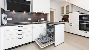 A modern kitchen with white cabinetry, a black countertop, and a dishwasher.