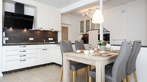 A modern kitchen with white cabinets, a wooden dining table, and grey chairs.