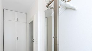 A hallway with a white wardrobe, a door, and a window.