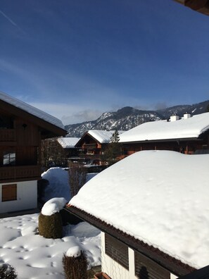 A snow-covered mountain village with wooden buildings and a clear sky. - 5-star apartment with balcony and views of the surrounding mountains (Reit im Winkl)
