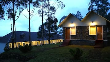 A two-story house with a stone facade, a wooden deck, and a well-lit entrance.