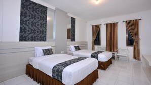 A hotel room with two beds, a desk, and a chair.