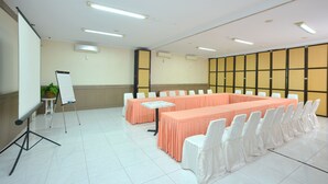 A conference room with a long table, white chairs, a whiteboard, and a projector.