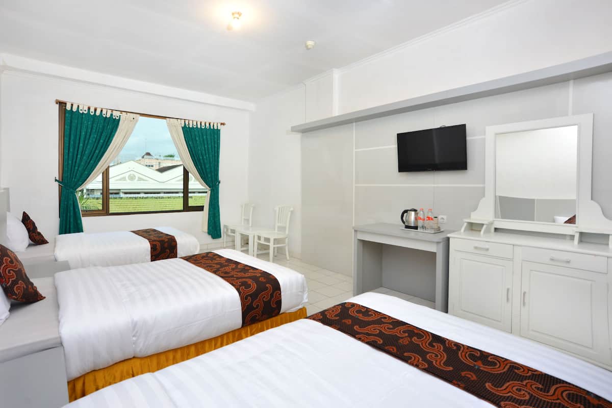 Una habitación de hotel con dos camas, un escritorio, una televisión y una ventana con cortinas.