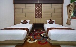 Habitación de hotel con dos camas, cabecero de madera, panel decorativo en la pared y alfombra colorida.