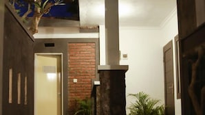 Un intérieur moderne avec un mur en briques, un pilier en pierre et diverses plantes en pot.
