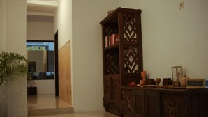 Un couloir avec une armoire en bois, une plante en pot et un sol carrelé.