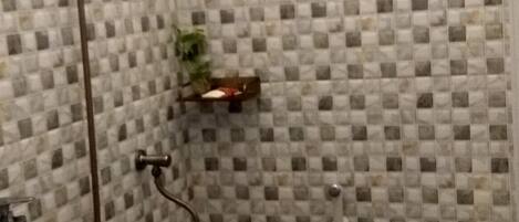 Un baño con pared de ducha azulejada, inodoro y ducha.