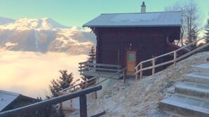 A wooden cabin with a metal staircase leading up to a door, surrounded by snow-covered ground and a mountain in the background. - Outside : 2-storey flat in a typical chalet in Chandolin, for 5 persons, beautiful terrace with nice (Chandolin)