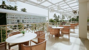 A covered outdoor seating area with wicker furniture and a view of a building with balconies. - Club Samal Resorts Development Inc (Samal)