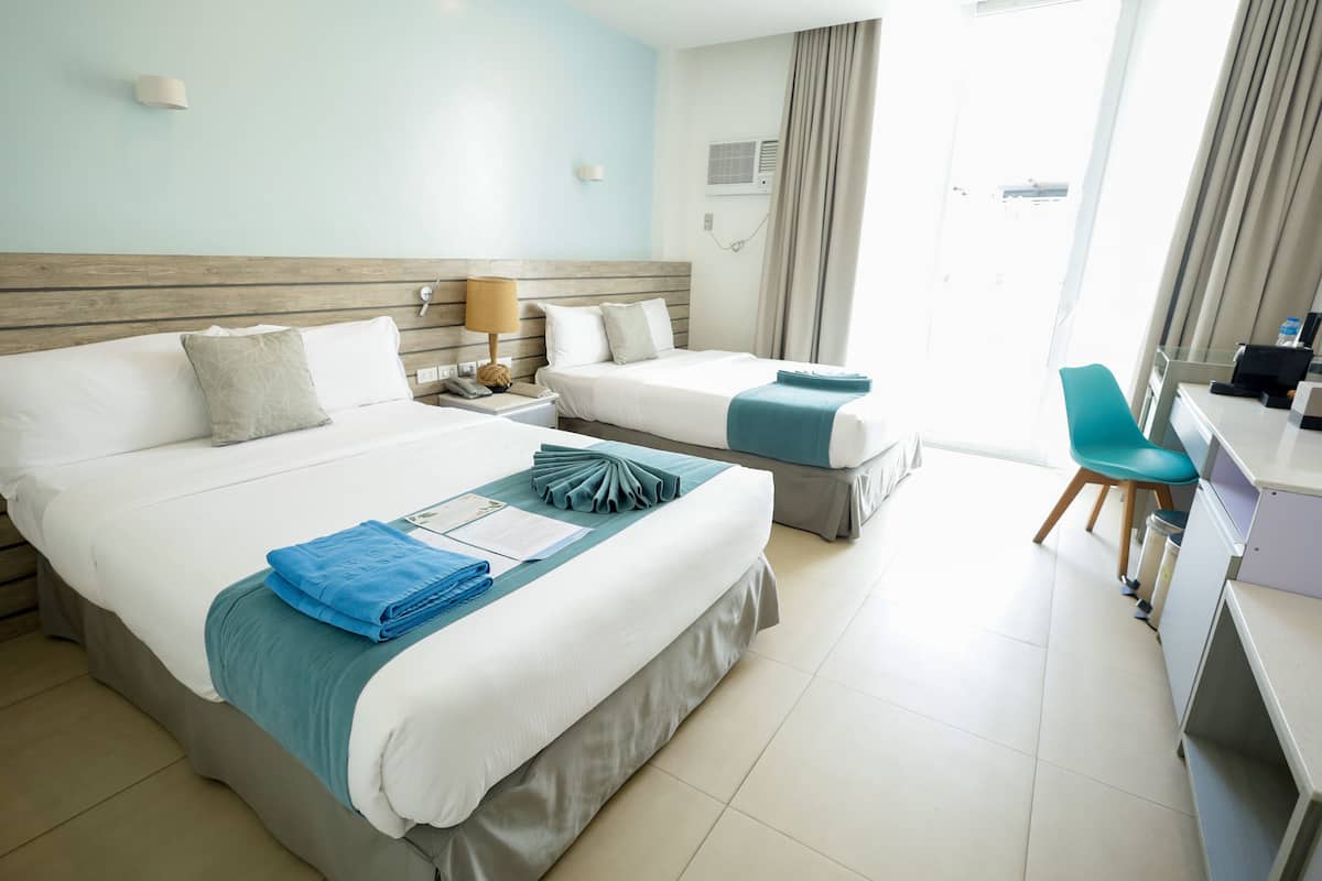 A hotel room with two beds, a desk, and a chair.
